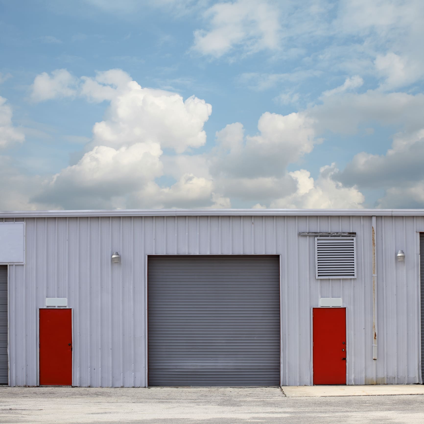 Warehouse with red doors under cloudy sky.